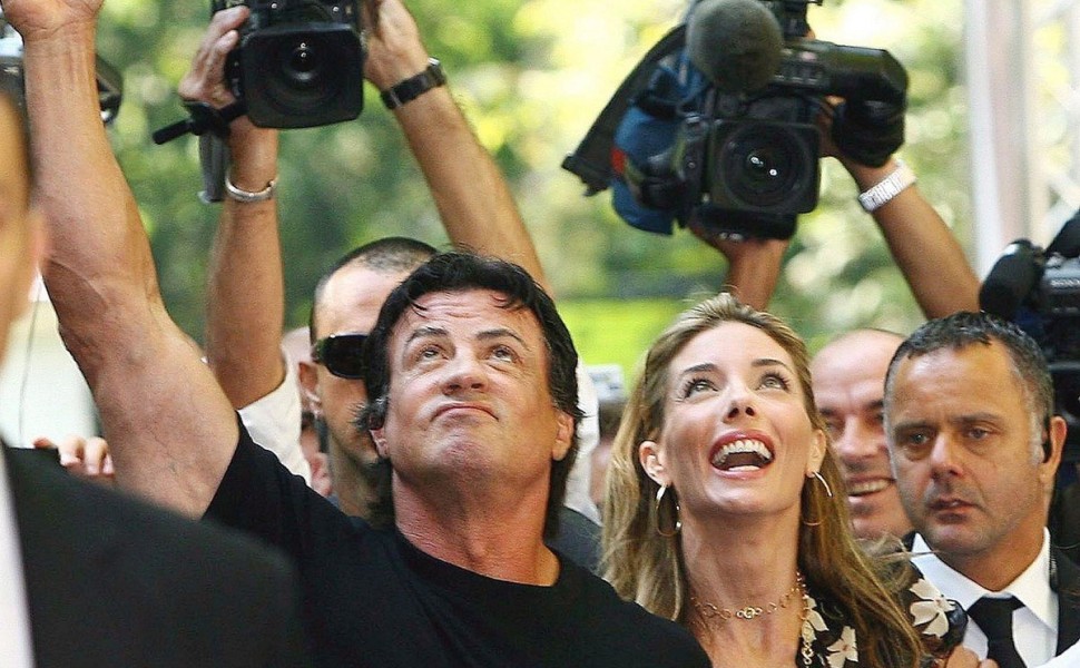 epa00824708 US actor Sylvester Stallone (L)  and his wife Jennifer Flavin are surrounded by bodyguards, photographers and cameramen upon their arrival in Salsomaggiore Terme on Friday 22 September 2006. Stalone will attend as president of the jury the fin