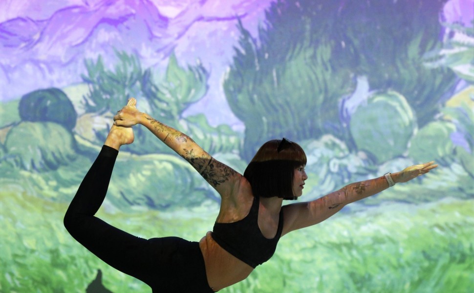 epa10785322 A Yoga enthusiast performs a yoga exercise in front of the projection of a Van Gogh painting amid immersive art during an Immersive Brew Yoga at the Van Gogh Alive exhibition in Bangkok, Thailand, 05 August 2023. Thai and foreign Yoga enthusia