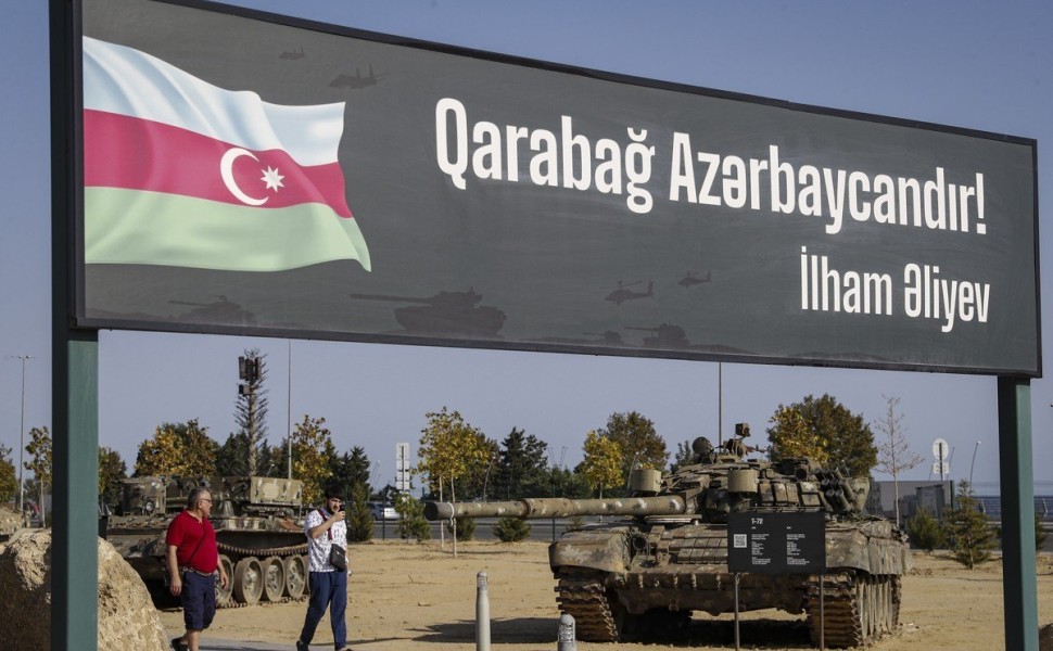 epa10856751 People walk next to a poster 'Karabakh is Azerbaijan! Ilham Aliev' at the Military Trophy Park, containing war trophies seized by the Armed Forces of Azerbaijan from the Armenian Army and the Artsakh Defence Army during the 2020 Nagorno-Karaba