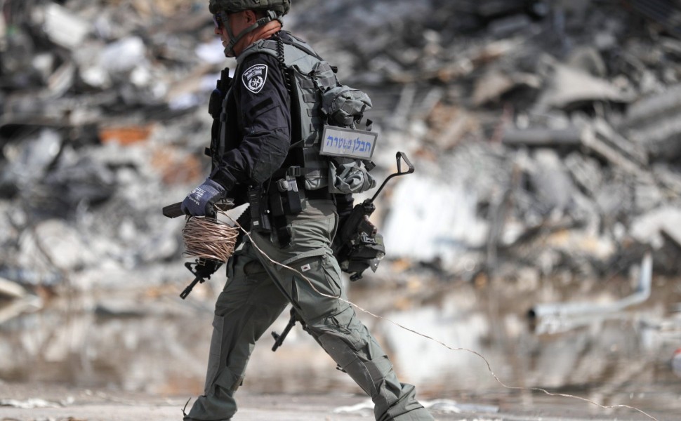 epa10907050 A member of the Israeli security forces carries a weapon used by Hamas fighters at the site of the destroyed police station that was controlled by Hamas militants in the southern city of Sderot, close to the Gaza border, Israel, 08 October 202