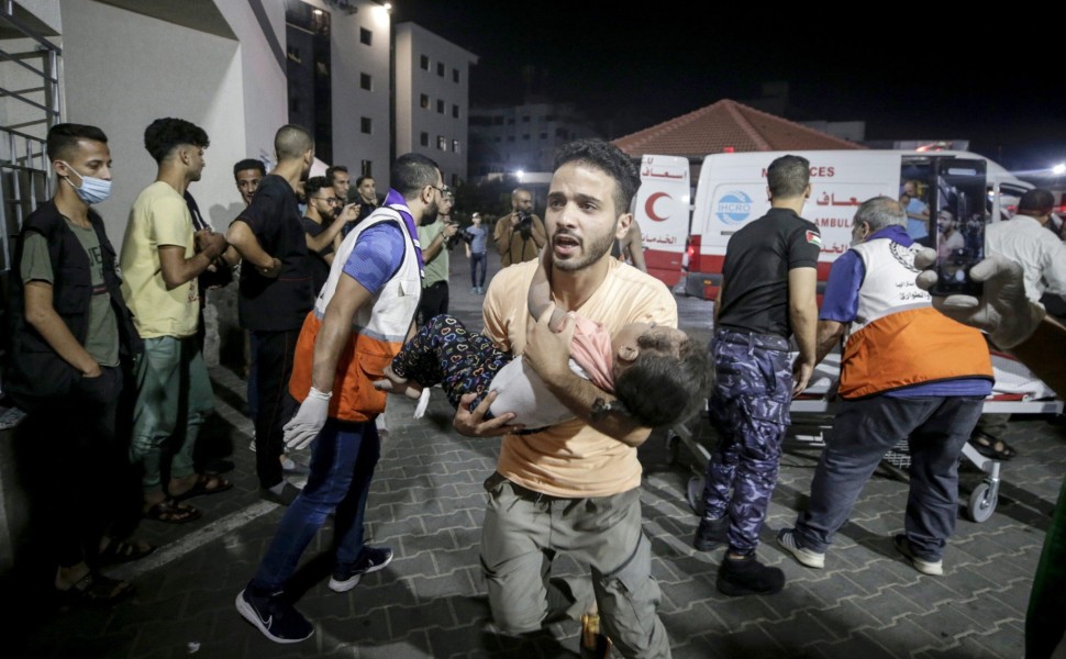 epa10908850 A Palestinian man carries a wounded child at Al-Shifa hospital in Gaza City, 09 October 2023. The Israeli army announced on 09 October, it carried out over 500 strikes on targets across the Gaza Strip overnight. Palestinian officials said almo