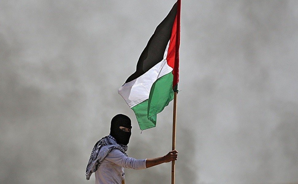 epa06651632 A Palestinian protester holds a Palestinian flag during clashes with Israeli toops near the border with Israel in the east of Jabaliya refugee camp in the northern Gaza Strip, 06 April 2018, (issued 07 April 2018). Palestinian Islamist group H