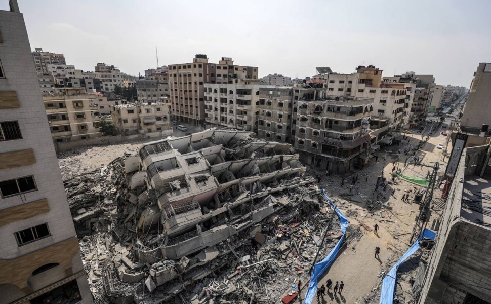 epa10907219 An aerial view shows people gathering near the destroyed Al-Aklouk Tower following Israeli air strikes, in Gaza City, 08 October 2023. The air strikes, in retaliation for the 07 October Hamas rocket attacks on Israel, have killed over 300 peop