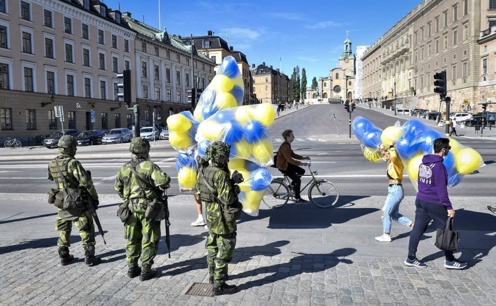 epa06788760 Reservist soldiers standing guard watch over people passing by while holding yellow and blue balloons near the Stockholm Palace during a military training exercise in Stockholm, Sweden, 06 June 2018, on the country's national day. It is the fi