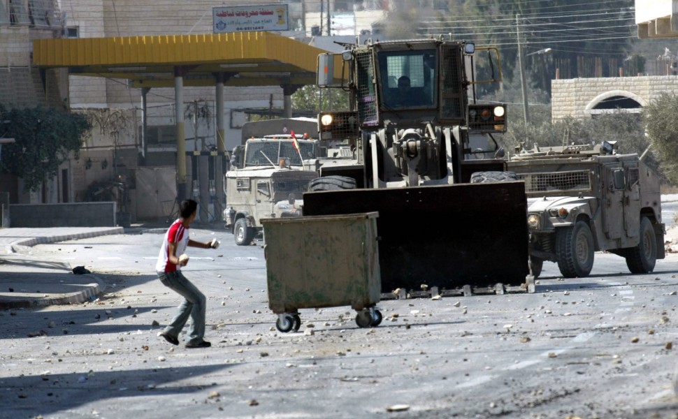epa000288544 A Palestinian boy hurls stones at an Israeli bulldozer during clashes in Qabatya village, near the West Bank city of Jenin, during an army operation in the village, Tuesday 05 October 2004. Witnesses said that Israeli soldiers took positions 
