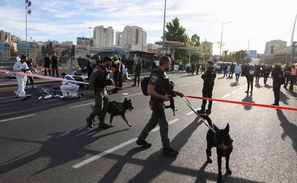 Αστυνομικοί με ειδικές στολές εξετάζουν το σημείο της επίθεσης στην είσοδο της Ιερουσαλήμ, ενώ άλλοι αστυνομικοί «χτενίζουν» την περιοχή για εκρηκτικά λίγα λεπτά μετά την τρομοκρατική επίθεση / Reuters