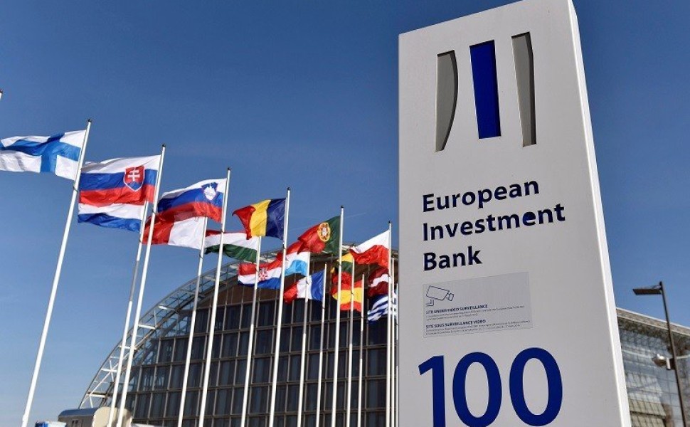 FILE PHOTO: Flags are seen behind the logo of the European Investment Bank pictured in the city of Luxembourg, Luxembourg, March 25, 2017. Reuters/Eric Vidal/File Photo