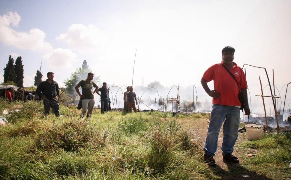 Μετανάστες εργάτες γης μετά από πυρκαγιά σε καταυλισμό τους.