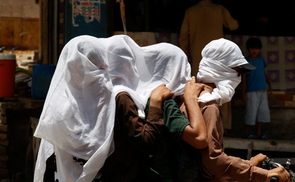 Κάτοικοι του Πακιστάν προσπαθούν να προφυλαχθούν από την ακραία ζέστη, κυκλοφορώντας με βρεγμένα λευκά πανιά στο κεφάλι τους / REUTERS