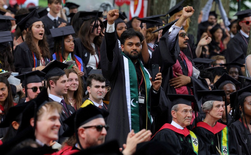Ένας από τους 13 φοιτητές που δεν μπόρεσαν να αποφοιτήσουν επειδή συμμετείχαν σε διαδηλώσεις υπέρ των Παλαιστινίων, σηκώνει τη γροθιά του κατά τη διάρκεια τελετής έναρξης στο Χάρβαρντ. Reuters