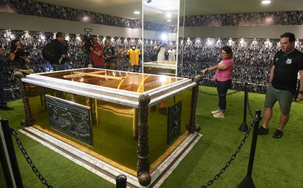 Fans stand next to the tomb of the late Brazilian soccer great Pele which became open to the public for the first time, at the mausoleum of Necropole Ecumenica Memorial Cemetery in Santos, Brazil, Monday, May 15, 2023. (AP Photo/Andre Penner)